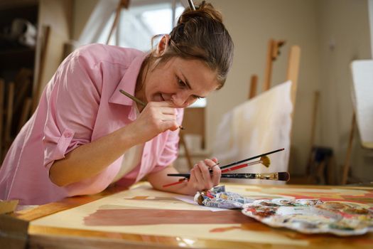 Art, creativity, hobby and creative occupation concept. Bringing creativity to life. Woman painting in art studio. Attractive female artist painting in workshop. Woman hobby, activity, profession.