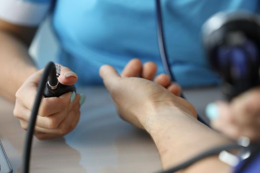 Cardiologist measuring blood pressure to patient in clinic closeup. Principles of arterial hypertension treatment concept