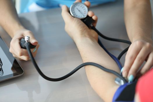 Doctor measuring patient blood pressure on arm using tonometer closeup. Diagnosis and treatment of arterial hypertension concept