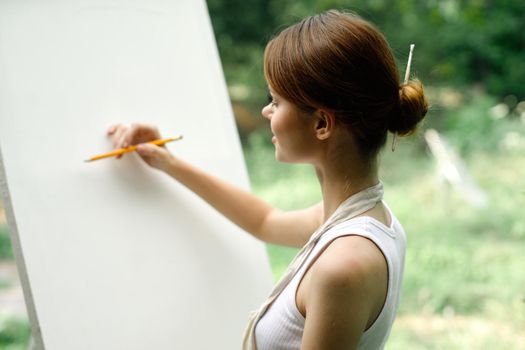 an artist in nature draws on an easel with a pencil. High quality photo