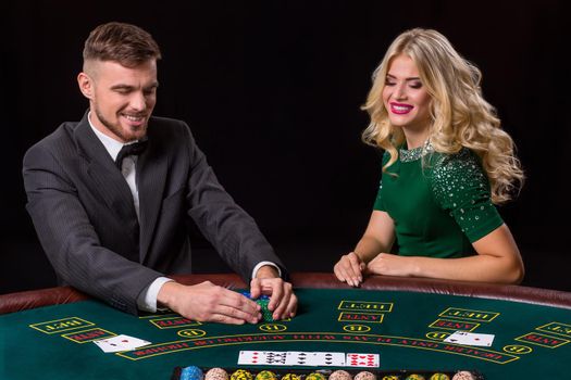 couple playing poker at the green table. The blonde girl and a guy in a suit. happy win