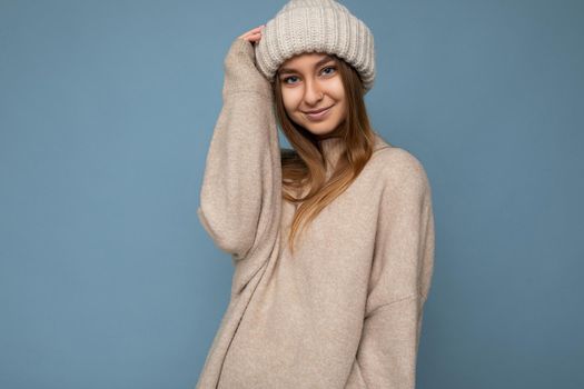 Attractive smiling happy young blond woman standing isolated over colorful background wall wearing everyday stylish outfit showing facial emotions looking at camera.