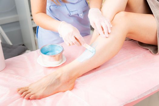 Cosmetology concept. Sugar and waxing depilation of the feet in the beauty salon. Rid of hair on the legs. Sugaring. Master cosmetologist removing hair on the legs. Beautician in the spa center.