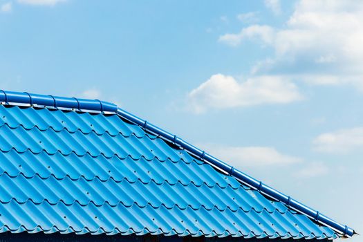 Blue tiles of the roof of a house or building against the cloud sky.