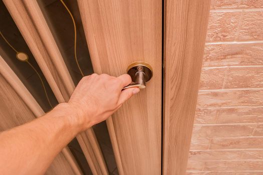 Guy's hand opens or closes a wooden door with glass trims.