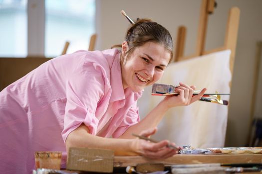 Art, creativity, hobby and creative occupation concept. Bringing creativity to life. Woman painting in art studio. Attractive female artist painting in workshop. Woman hobby, activity, profession.