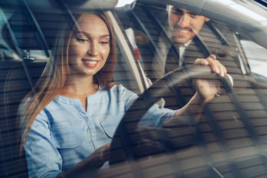 Attractive young woman sitting in new car in showroom close up