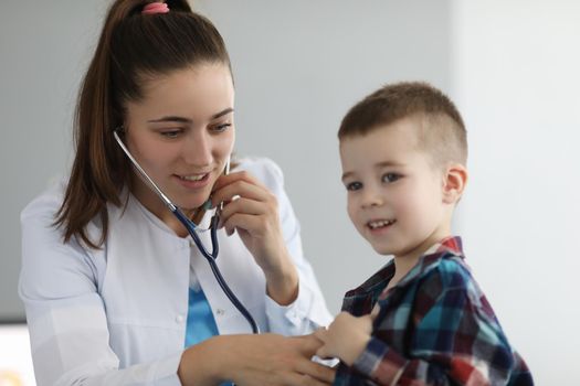 Doctor pediatrician listening to heart with stethoscope to little boy in clinic. Diagnosis of heart and lung disease in children concept