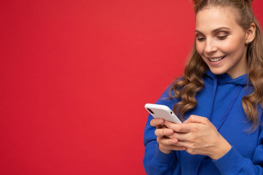 Image of a shocked young beautiful woman posing isolated over red wall background play games by mobile phone