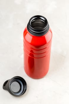 Red reusable steel thermo water bottle with open cap over grey background, Zero waste, Refill concept