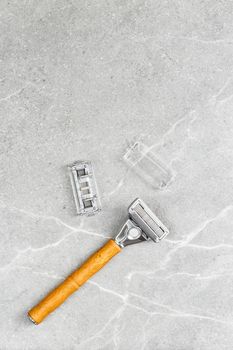 Shaving Razor with wooden handle with refill blade on a grey marble background. Plastic free hygiene tool