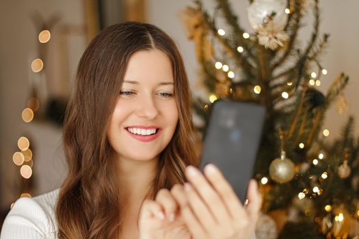 Christmas phone call and holiday greeting concept. Happy smiling woman using mobile smartphone on xmas day.