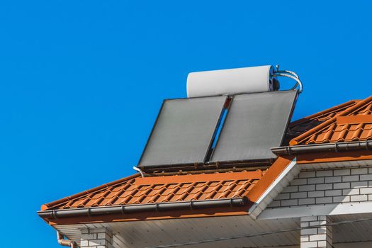 Solar water heater on the roof of a hotel against the background of the blue sky. Using solar energy to heat water.