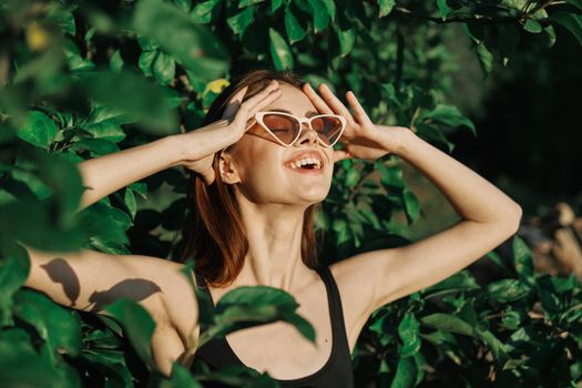 smiling woman wearing sunglasses green leaves nature fashion. High quality photo