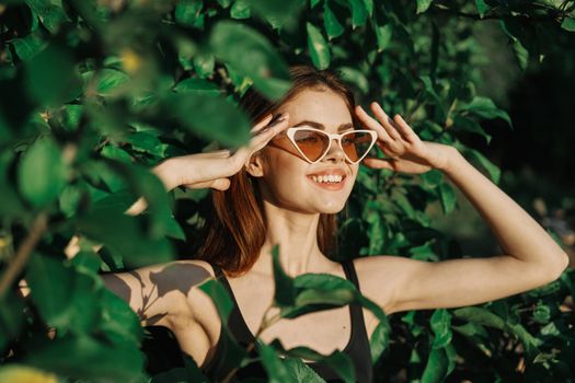 smiling woman wearing sunglasses green leaves nature fashion. High quality photo