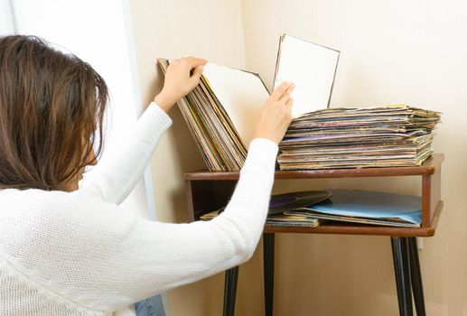 Woman choosing vinyl records at home for listening.