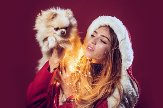 Woman with pomeranian spitz dog at xmas. Girl in santa costume with pet. Christmas and winter holiday. New year of dog.