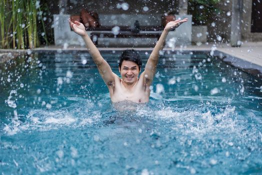 young man in swimming pool and playing water splash