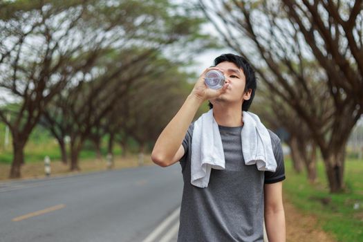 young sporty man drinking water in the park