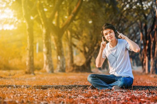 young man listening to music with headphones from mobile in the park