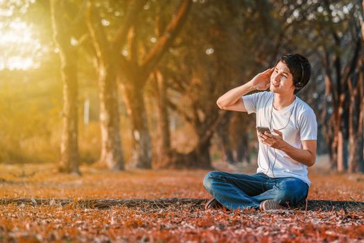 young man listening to music with headphones from mobile in the park