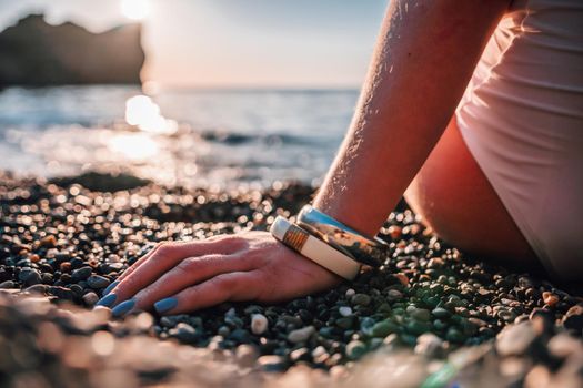 Young woman in swimsuit with long hair practicing stretching outdoors on yoga mat by the sea on a sunny day. Women's yoga fitness pilates routine. Healthy lifestyle, harmony and meditation concept.