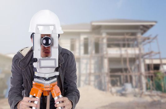 Engineers use tacheometer or theodolite with building construction site background