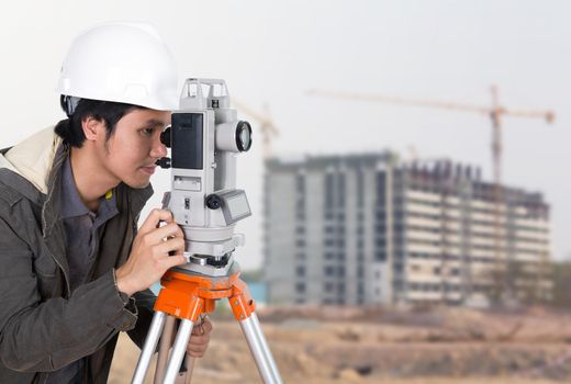 Engineers use tacheometer or theodolite with building construction site background