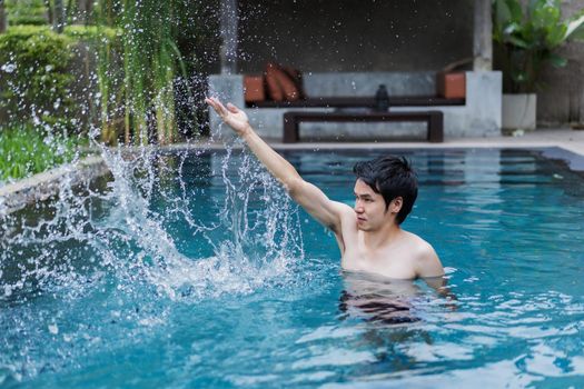 young man in swimming pool and playing water splash