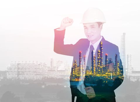 Double exposure of  engineer celebrating with arm raised against the Petrochemical Industrial plant