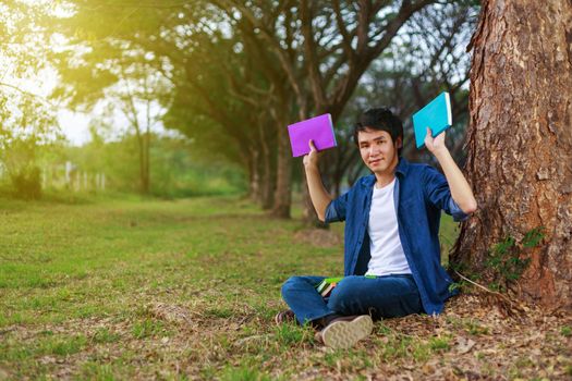 young man sitting and holding a book in the park