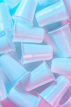 Various disposable plastic cups on a light background in pastel colors. Minimalistic ecologically clean still life. Pop Art. And ecology problem concept.