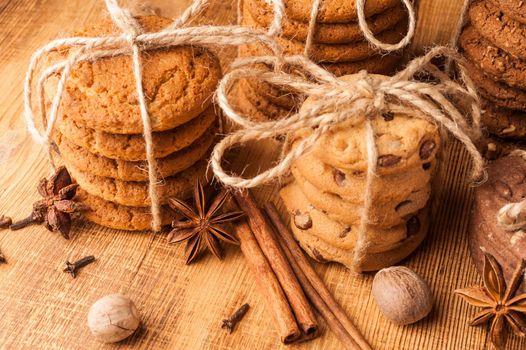 Homemade corded wholegrain cookies with oatmeal, linen and sesame seeds and traditional cookies with chocolate chips on dark rustic wooden table and spice.