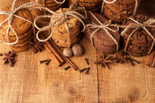 Homemade corded wholegrain cookies with oatmeal, linen and sesame seeds and traditional cookies with chocolate chips on dark rustic wooden table and spice. Copy space.