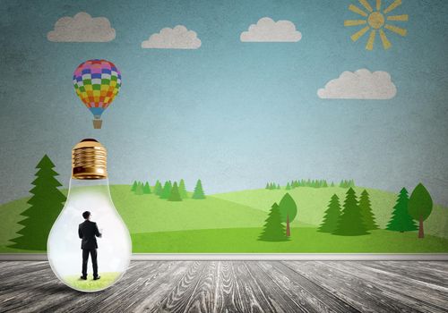 Businessman inside light bulb in room against nature drawn concept