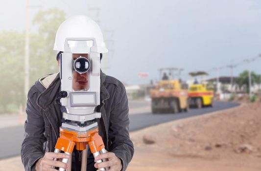 engineer working with survey equipment theodolite with road under construction background