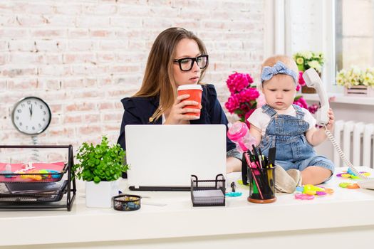 Businesswoman mother woman with a daughter working at the computer. At the workplace, together with a small child