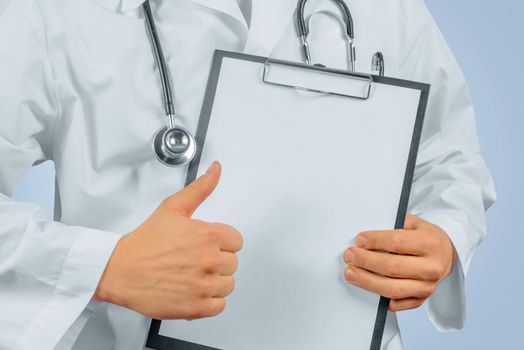 Unrecognizable man doctor shows gesture thumb up in front of clipboard, space for text