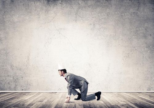Young handsome businessman wearing white paper crown running in a hurry