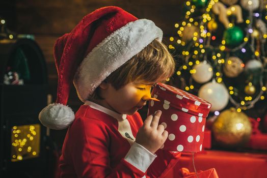 Surprised boy child open christmas gift near christmas tree. Lovely baby enjoy christmas. Funny kids face closeup