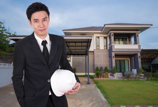 engineer holding helmet with modern house background