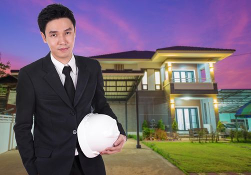 engineer holding helmet with modern house background