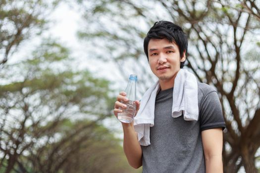 young sporty man with bottle of water in the park