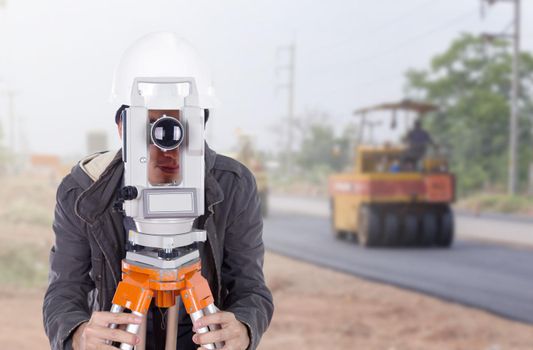 engineer working with survey equipment theodolite with road under construction background