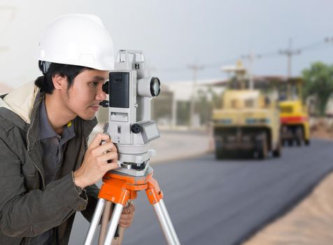 engineer working with survey equipment theodolite with road under construction background