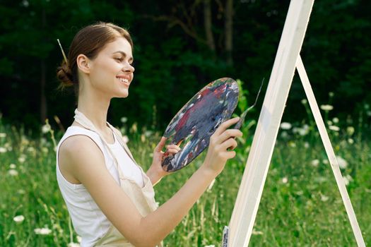 cheerful woman paints a picture palette nature landscape. High quality photo