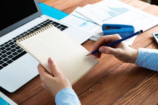 close-up, female hands with notebook and pencil. Business woman working at the table in the office
