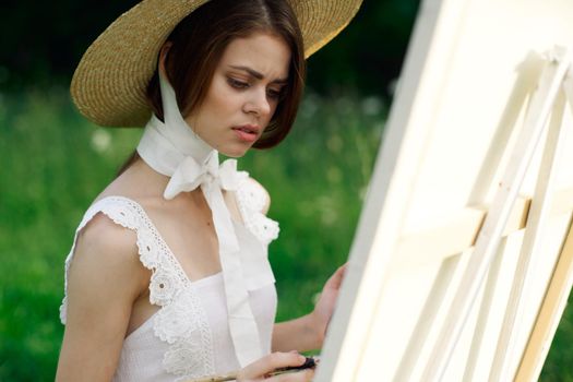 woman artist in hat with brush paints a picture. High quality photo