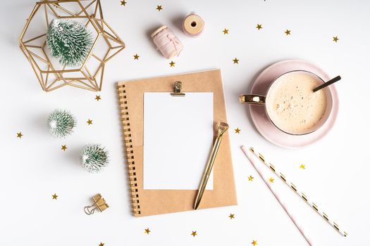 Desktop blank planner. Flat lay of white working table background with cup of coffee and Christmas decoration. Top view balls, fir tree, paper clips, mock up greeting card, craft Notebook and pen.