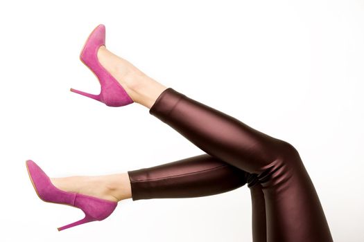 Woman in leather pants and pink high heels shoes on a white background. - image